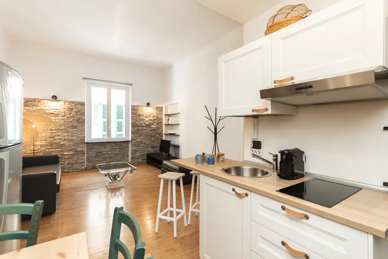 Cucina con muro in pietra e tavolo da pranzo, appartamento in affitto breve a Genova gestito da Immobirent